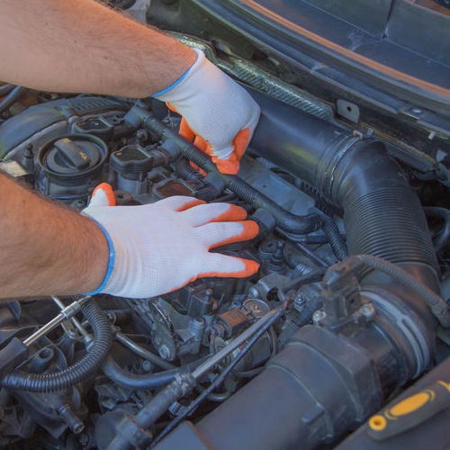 An Automotive Technician Works on a Tune Up.