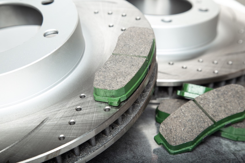 Brake pad and perforated brake discs on a dark gray table