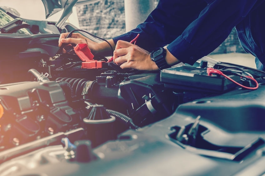 Auto mechanic checking car battery voltage