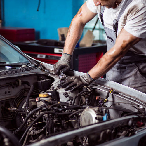 Mechanic tinkering with engine, including serpentine belt